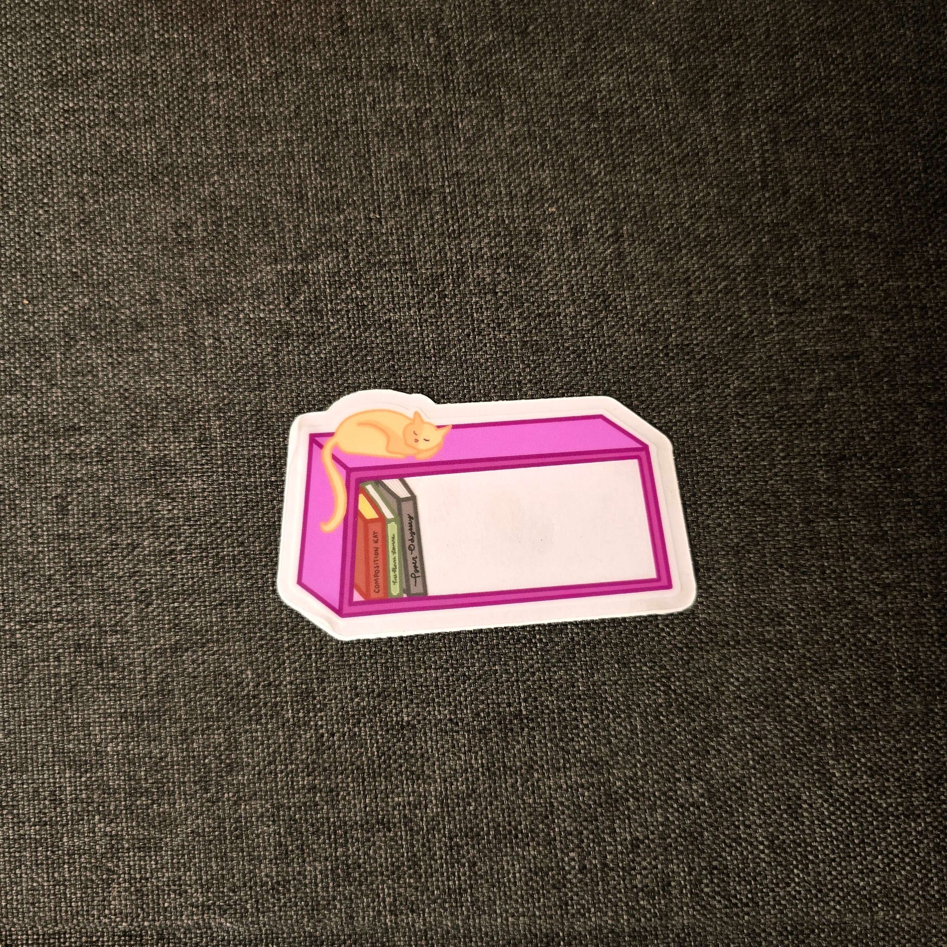an orange cat sleeping on a bookshelf peacefully. The sticker has a clear window and is made of high quality soft touch vinyl.